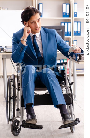 Male employee in wheelchair working at the office 94404407