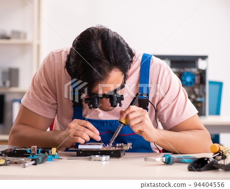 The young male contractor repairing computer The young male contractor repairing computer 94404556