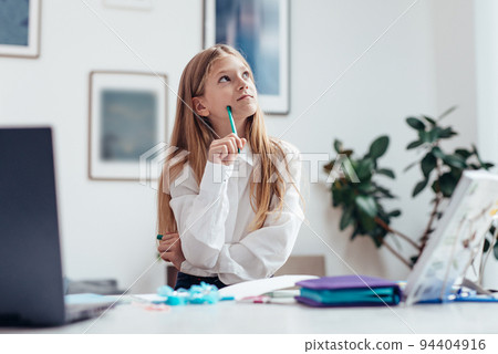 Girl is doing her homework and sits staring thoughtfully to the side Girl is doing her homework and sits staring thoughtfully to the side 94404916