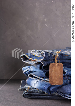 Blue jeans denim heap on table background. Jeans fabric material and tag price label Blue jeans denim heap on table background. Jeans fabric material and tag price label 94404965