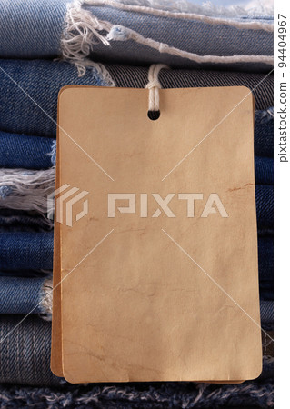Blue jeans denim heap on table background. Jeans fabric material and tag price label Blue jeans denim heap on table background. Jeans fabric material and tag price label 94404967