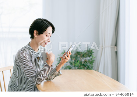 Middle-aged woman drinking coffee in a mug Middle-aged woman drinking coffee in a mug 94406014