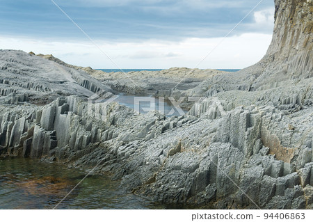 coastal cliffs formed by columnar basalt at low tide 94406863