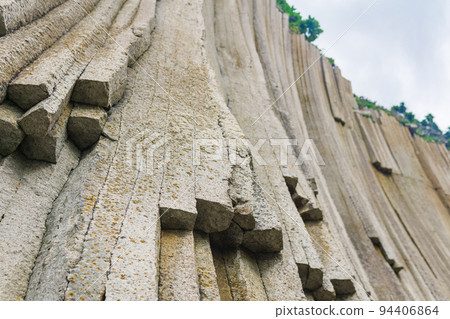 basalt columns forming a coastal rock at Cape Stolbchaty on Kunashir Island, close-up 94406864