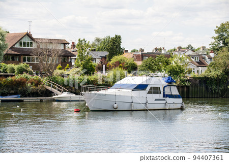 A cruiser moored on the River Thames and a brick building in Richmond on the outskirts of London A cruiser moored on the River Thames and a brick building in Richmond on the outskirts of London 94407361