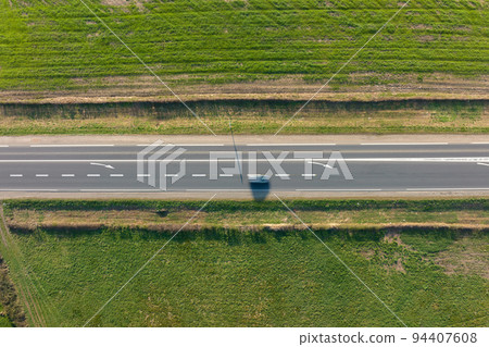 Aerial view of intercity road between green agricultural fields with fast driving cars. Top view from drone of highway traffic 94407608