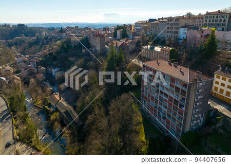 Aerial view of dense historic center of Thiers town in Puy-de-Dome department, Auvergne-Rhone-Alpes region in France. Rooftops of old buildings and narrow streets 94407656