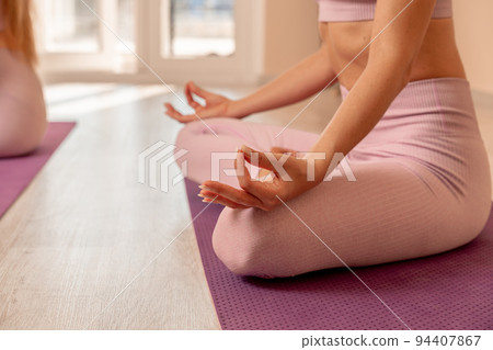 Middle aged woman looks good, practicing yoga, fitness, sports, training, woman doing exercises. She is wearing a pink top and leggings. The concept of grace and beauty of the body 94407867