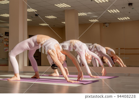 Two beautiful women cook doing yoga, sports together in the gym. Dressed in pink suits. The concept of grace and beauty of the body. 94408228