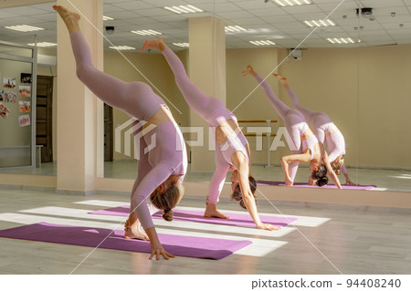 Two beautiful women cook doing yoga, sports together in the gym. Dressed in pink suits. The concept of grace and beauty of the body. 94408240