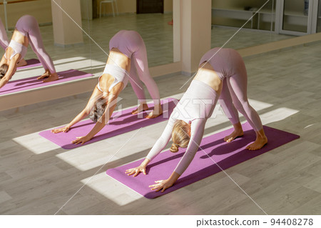 Two beautiful women cook doing yoga, sports together in the gym. Dressed in pink suits. The concept of grace and beauty of the body. 94408278