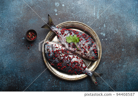 Raw fish dorado with pink peppercorn for healthy cooking top view Raw fish dorado with pink peppercorn for healthy cooking top view 94408587