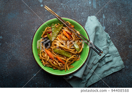 Asian stir fry noodles with chicken and veggies in green bowl top view Asian stir fry noodles with chicken and veggies in green bowl top view 94408588