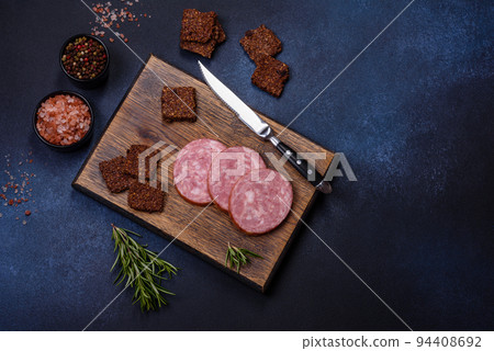 Delicious fresh smoked sausage cut with slices on a wooden cutting board 94408692