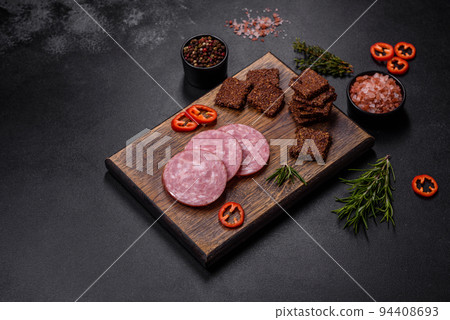 Delicious fresh smoked sausage cut with slices on a wooden cutting board 94408693