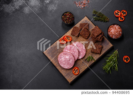 Delicious fresh smoked sausage cut with slices on a wooden cutting board Delicious fresh smoked sausage cut with slices on a wooden cutting board 94408695