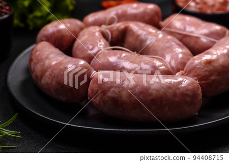 Raw barbecue sausages on a wooden cutting board with spices and herbs Raw barbecue sausages on a wooden cutting board with spices and herbs 94408715