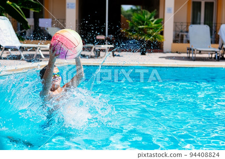 Teenage boy plays ball and has fun in the pool 94408824