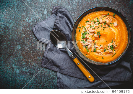 Bowl with pumpkin cream soup with peanuts on dark stone background 94409175