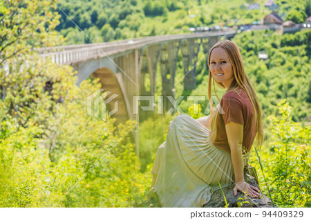 Montenegro. Woman tourist in background of Dzhurdzhevich Bridge Over The River Tara. Travel around Montenegro concept. Sights of Montenegro Portrait of a disgruntled girl sitting at a cafe table Montenegro. Woman tourist in background of Dzhurdzhevich Bridge Over The River Tara. Travel around Montenegro concept. Sights of Montenegro Portrait of a disgruntled girl sitting at a cafe table 94409329
