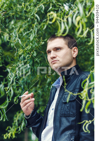 Closeup handsome young man smoking cigarette Closeup handsome young man smoking cigarette 94409410