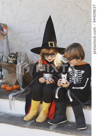 Kids in Halloween costumes are sitting on the porch 94409637