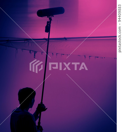 Boom Microphone for sound recording in film industry. Sound boom operator recording sound by microphone fisher for movie set in studio. Boom mic holds up high by video or film production crew team man Boom Microphone for sound recording in film industry. Sound boom operator recording sound by microphone fisher for movie set in studio. Boom mic holds up high by video or film production crew team man 94409883