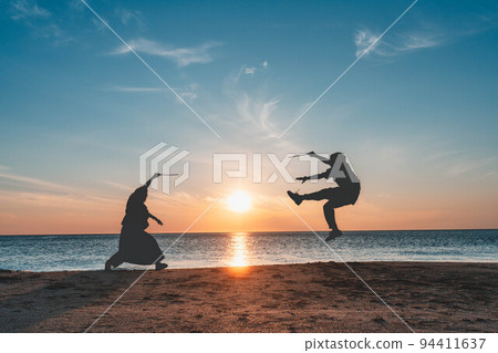 Men and women playing silhouettes at sunset in the Sea of Japan 94411637
