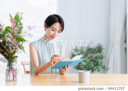Middle woman reading a book in the living room Middle woman reading a book in the living room 94411707