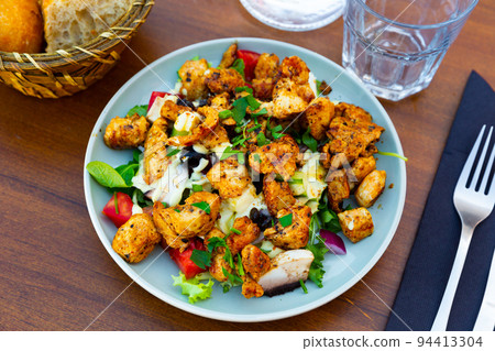 Warm Caesar salad with fried chicken and mushrooms close up 94413304