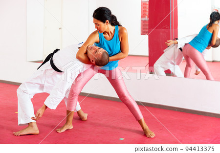 Woman exercising self-protection moves with trainer 94413375