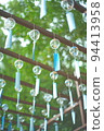 Many blue wind chimes and sunlight filtering through foliage 94413958