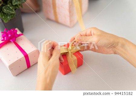 Woman tying a gift ribbon Woman tying a gift ribbon 94415182