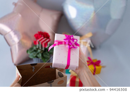 Woman taking out a gift from a paperback Woman taking out a gift from a paperback 94416308