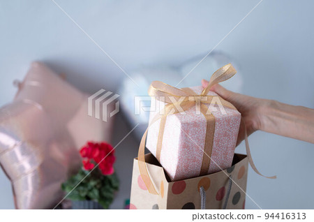 Woman taking out a gift from a paperback Woman taking out a gift from a paperback 94416313