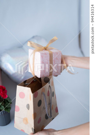 Woman taking out a gift from a paperback Woman taking out a gift from a paperback 94416314