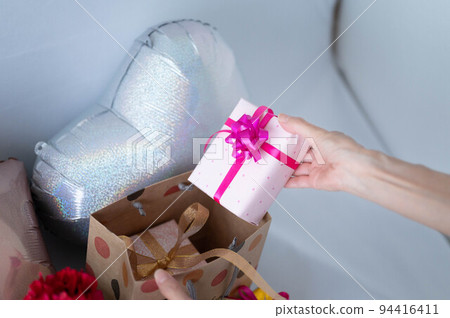 Woman taking out a gift from a paperback Woman taking out a gift from a paperback 94416411