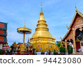 Beautiful view of Hariphunchai pagoda and surrounding chapels with blue sky and white cloud as background. This place is located in Lamphun province in the northern of Thailand. Complementary color. 94423080