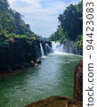 Beautiful flowing water of Tad Pha Suam waterfall located in Ba Chiang city, Champasak province, southern of Laos. Surrounded with many trees in the forest with blue sky and white cloud as background. 94423083