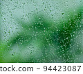 Closeup view of beautiful background of water drops pattern on scratched window glass while raining with blurry tree outside. Cool tone. 94423087