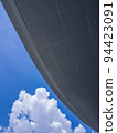 Bottom up view from under the roof of public building to the blue sky and white cloud. 94423091