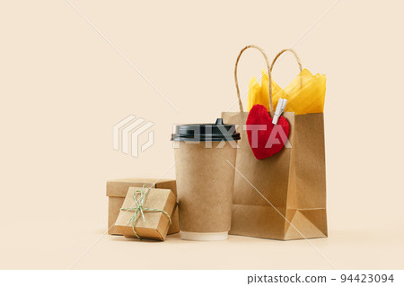 Takeaway paper coffee cup with lunch bag on beige Takeaway paper coffee cup with lunch bag on beige 94423094