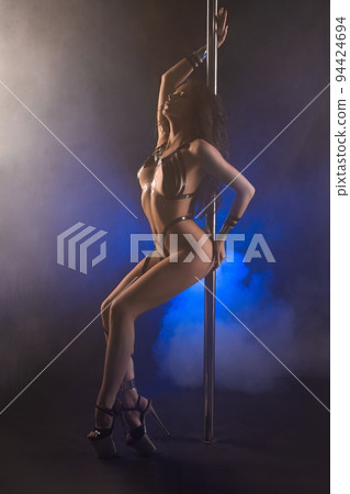 Sensual young woman in tape bodyart dancing near pole in studio 94424694