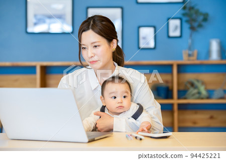 一個抱著嬰兒和操作電腦的女人 一個抱著嬰兒和操作電腦的女人 94425221