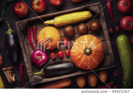 Pumpkin, tomato and other vegetables close-up in a wooden box autumn harvest. rustic background in a low key rustic carriage. 94425267