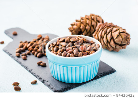 A bowl of unpeeled pine nuts and pine cones on a slate board. Detox and cure for insomnia. Healthy vitamin nutrition 94426422