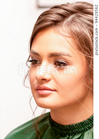 The fashionable young woman. Portrait of the beautiful female model with long hair and makeup. Beauty young caucasian woman with a brown curly hairstyle 94429562