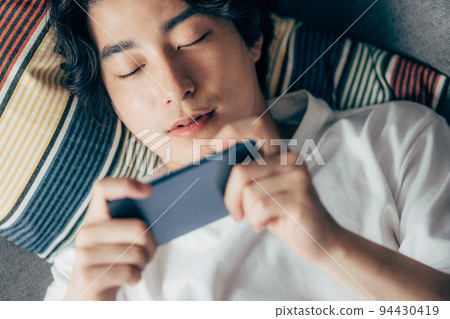 年輕人在沙發上使用智能手機 94430419