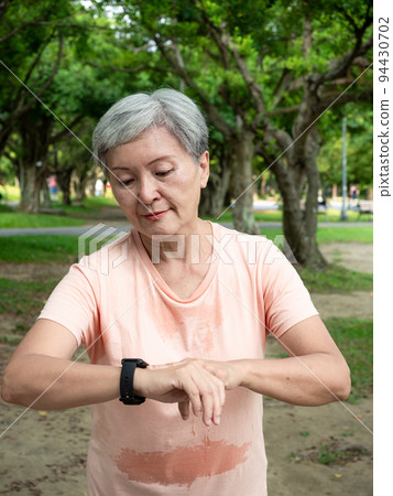 快樂的樂齡亞洲婦女微笑著草地上慢跑運動,並且享受公園裡的大自然新鮮空氣. 94430702