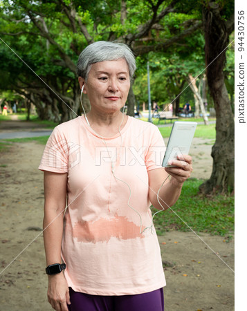 一位在地上微笑的亞洲女人演奏的令人愉悅的音樂。 94430756